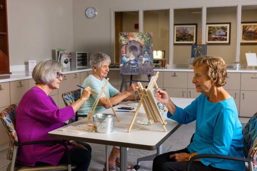 3 women painting in art class is one of the social activities for seniors available at Monarch Landing in Naperville, IL.