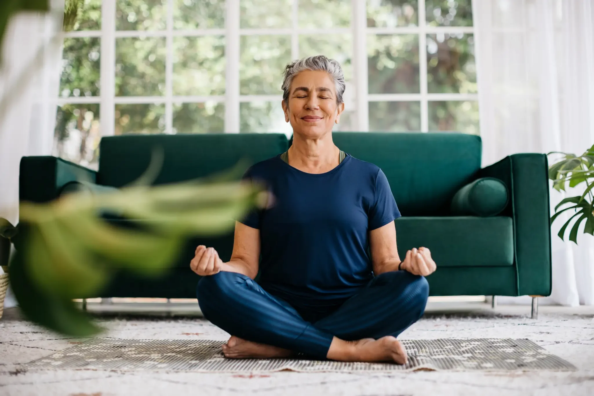 Senior woman in the Lotus Position in her living room
