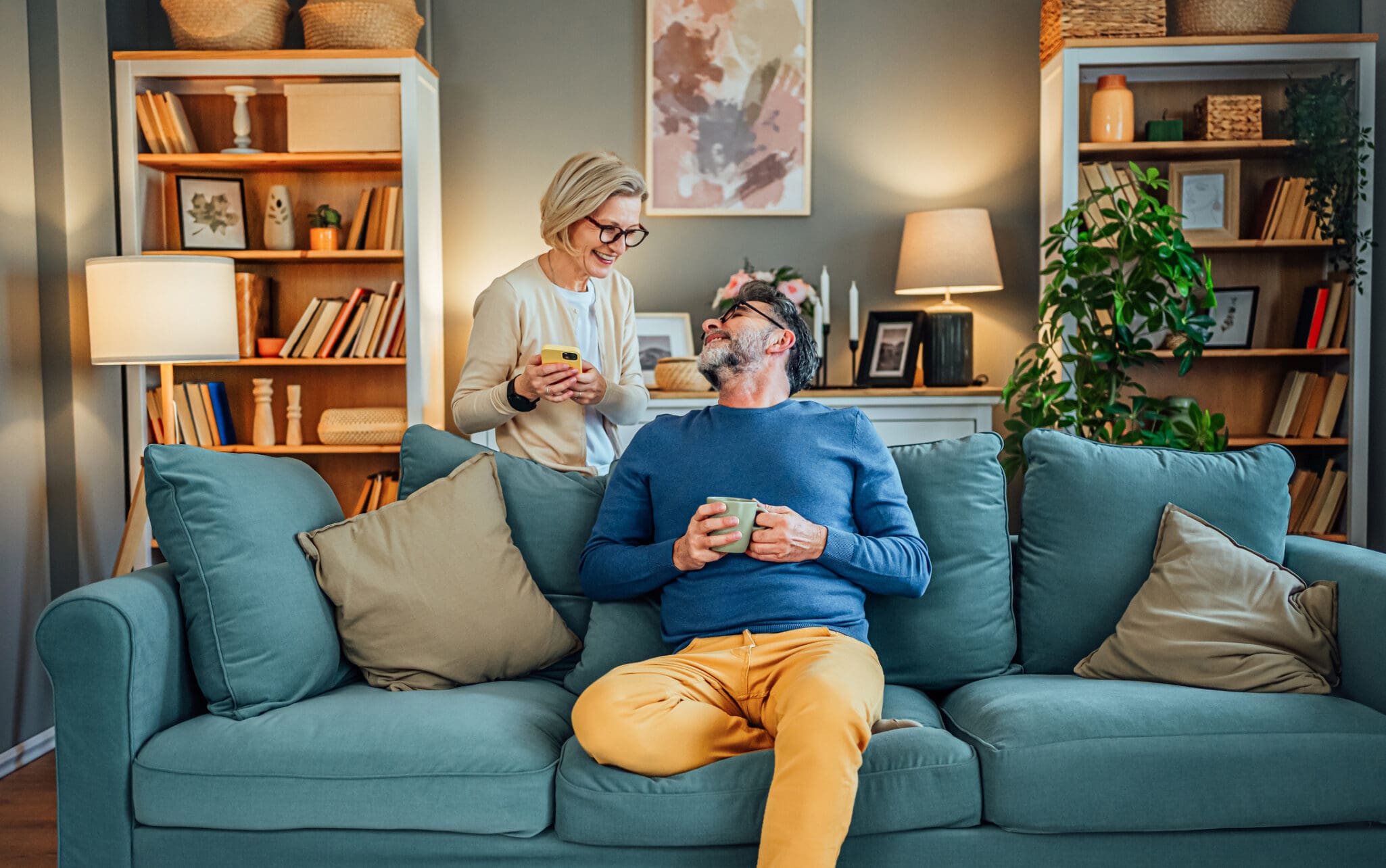 senior man sitting on couch looking up at senior woman