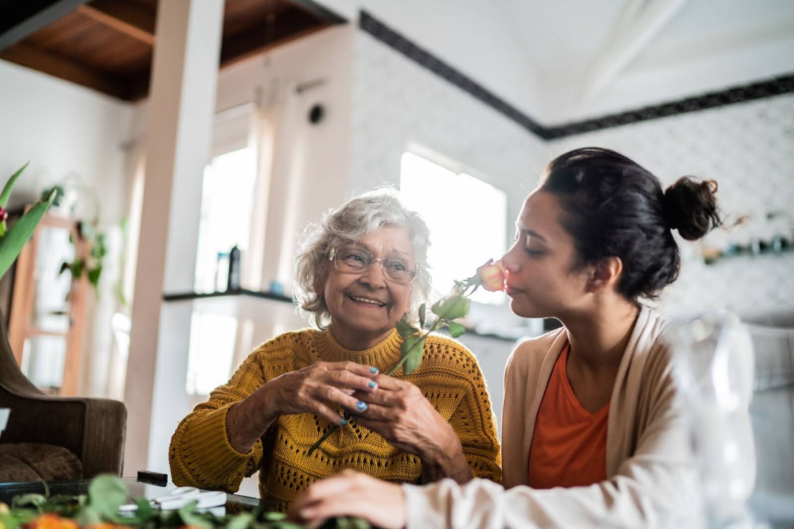 Senior lady and woman smelling flowers 
